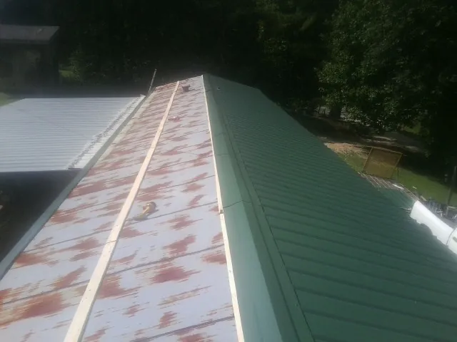 Old rusted panels beside newly installed green metal roofing — Wind Damage Roof Repair by Roofing Brothers in Nacogdoches
