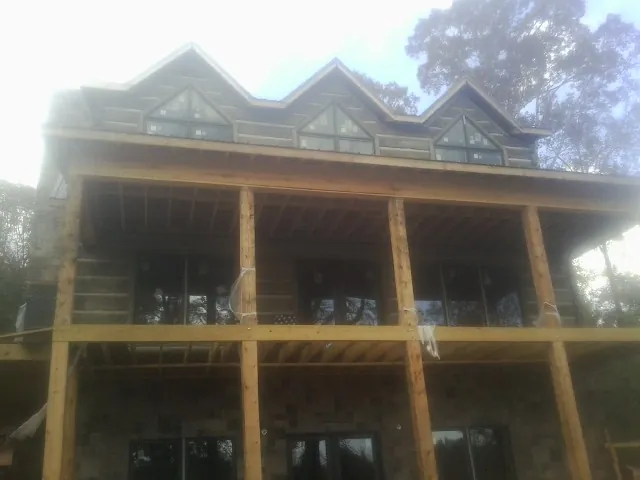 Dormers and porch framing on a large log home under construction — Roof Coating work by our crew in Nacogdoches