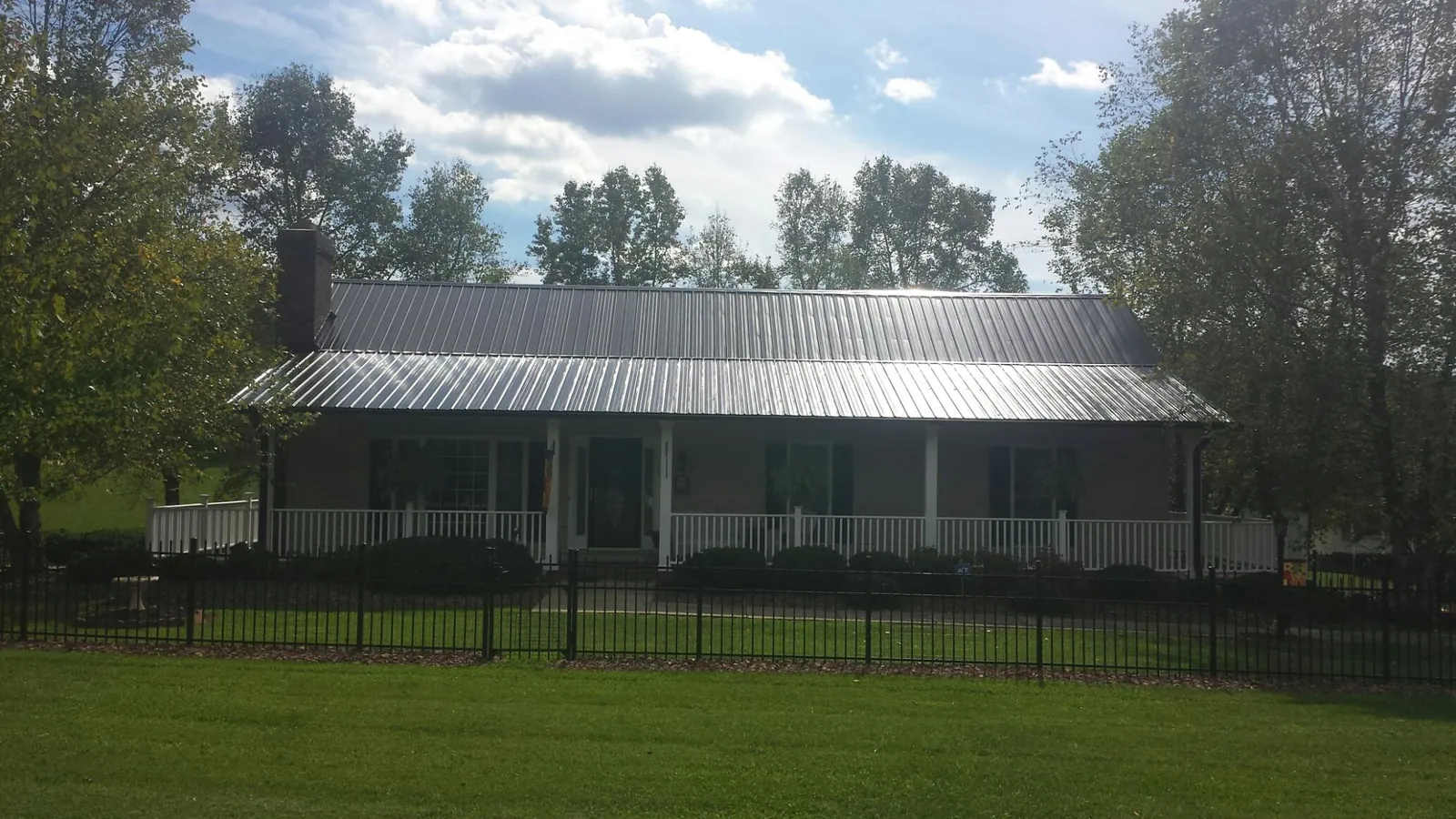 Gray metal roof on a brick ranch with a full width front porch — Gutter Guard Installation work by our crew in Nacogdoches