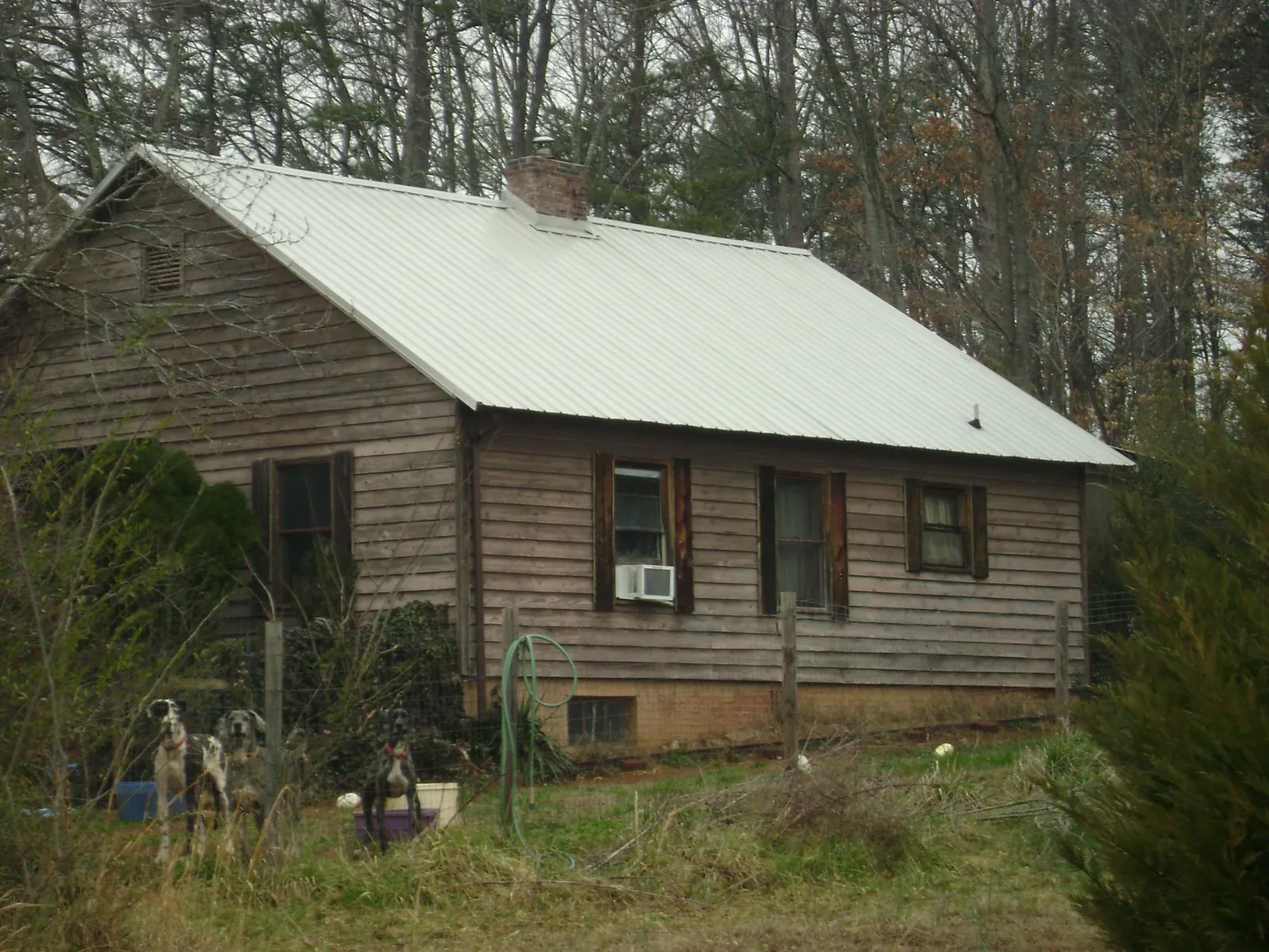 White metal roof on an old wood sided farmhouse, from a Metal Roof Installation job in Nacogdoches
