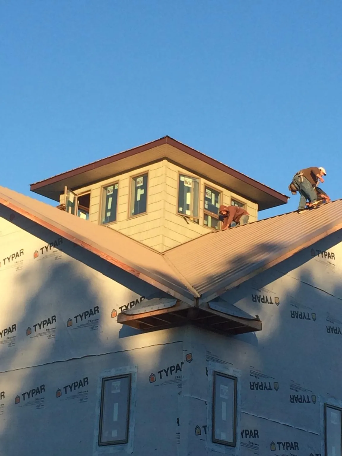 Roofers working around a rooftop cupola on a new metal roof at sunset — Roof Waterproofing in Nacogdoches by Roofing Brothers